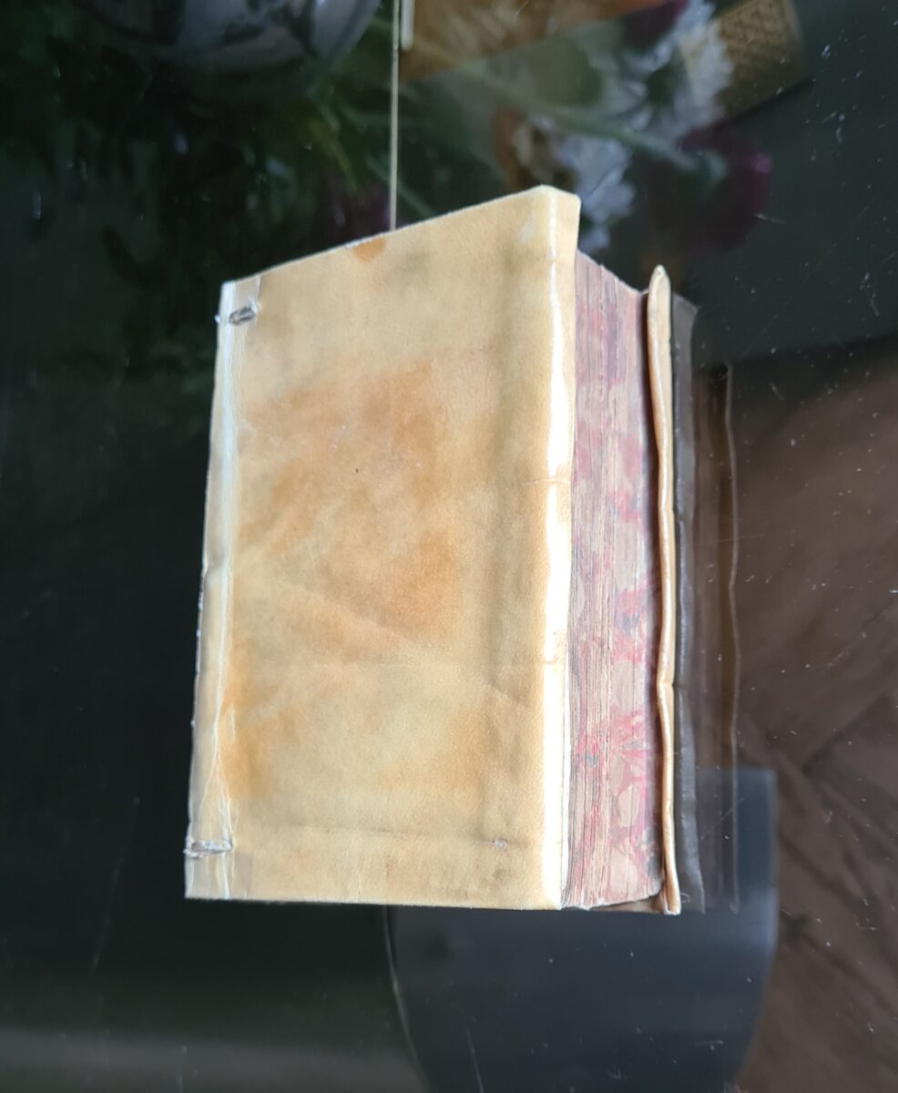 kleines, in pergament gebundenes altes buch auf einem glastich