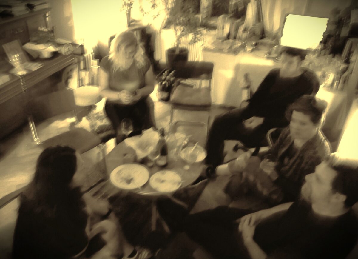 s/w-bild, in der mitte ein tisch, drumherum menschen im gespräch