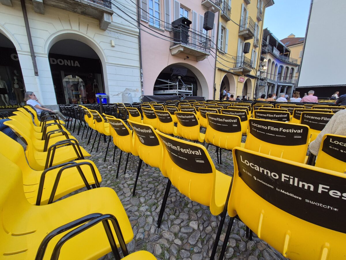 reihen von gelben plastikstühlen, hinten mit aufdruck "locarno film festival"